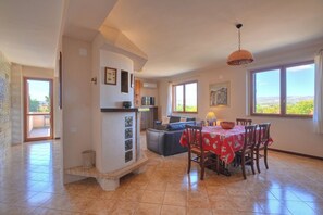 A spacious living area with a dining table, a sofa, and a kitchen area. - Villa Rubino, Elegant Country House with Pool (Syracuse)