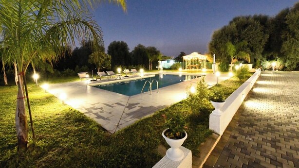 A swimming pool with lounge chairs and a gazebo, surrounded by trees and well-lit pathways. - Villa Il Ginepro, Family-Friendly near Syracuse (Floridia)