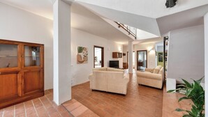 A spacious living area with a staircase, a wooden cabinet, and a television. - Villa Il Ginepro, Family-Friendly near Syracuse (Floridia)