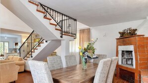 A dining area with a wooden table and chairs, a fireplace, and a staircase. - Villa Il Ginepro, Family-Friendly near Syracuse (Floridia)