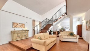 A spacious living area with a staircase, two sofas, a cabinet, and a painting on the wall. - Villa Il Ginepro, Family-Friendly near Syracuse (Floridia)