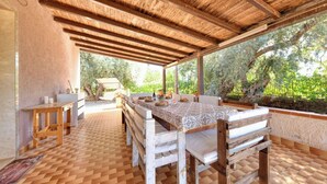 An outdoor covered patio with a dining table, benches, and a view of trees. - Villa Il Ginepro, Family-Friendly near Syracuse (Floridia)