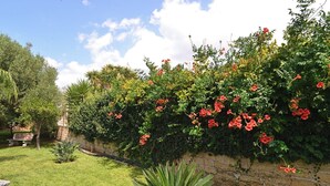 Een tuin met een stenen muur, een bankje en verschillende planten.