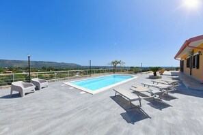 Ein Dachpool mit Liegestühlen, freie Aussicht auf die Landschaft und ein Gebäude mit rotem Dach.
