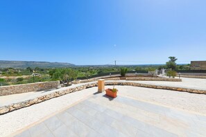 A rooftop terrace with stone walls, a potted plant, and a view of the countryside. - Villa Luce, close to town (Floridia)