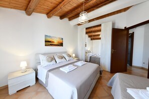 Ein Schlafzimmer mit einem Bett, Nachttischen, einem Gemälde und einer Holzbalkendecke.