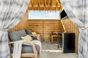 A cozy wooden cabin with a sofa, pillows, a small table, and a TV.