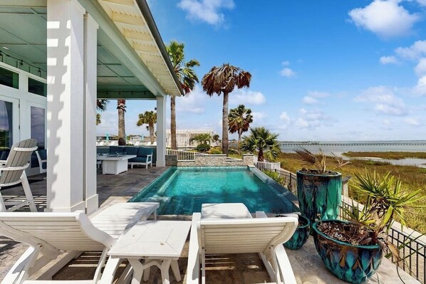 Un espace piscine avec des chaises longues et vue sur la plage.