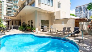 Une piscine avec des chaises longues et un espace barbecue.