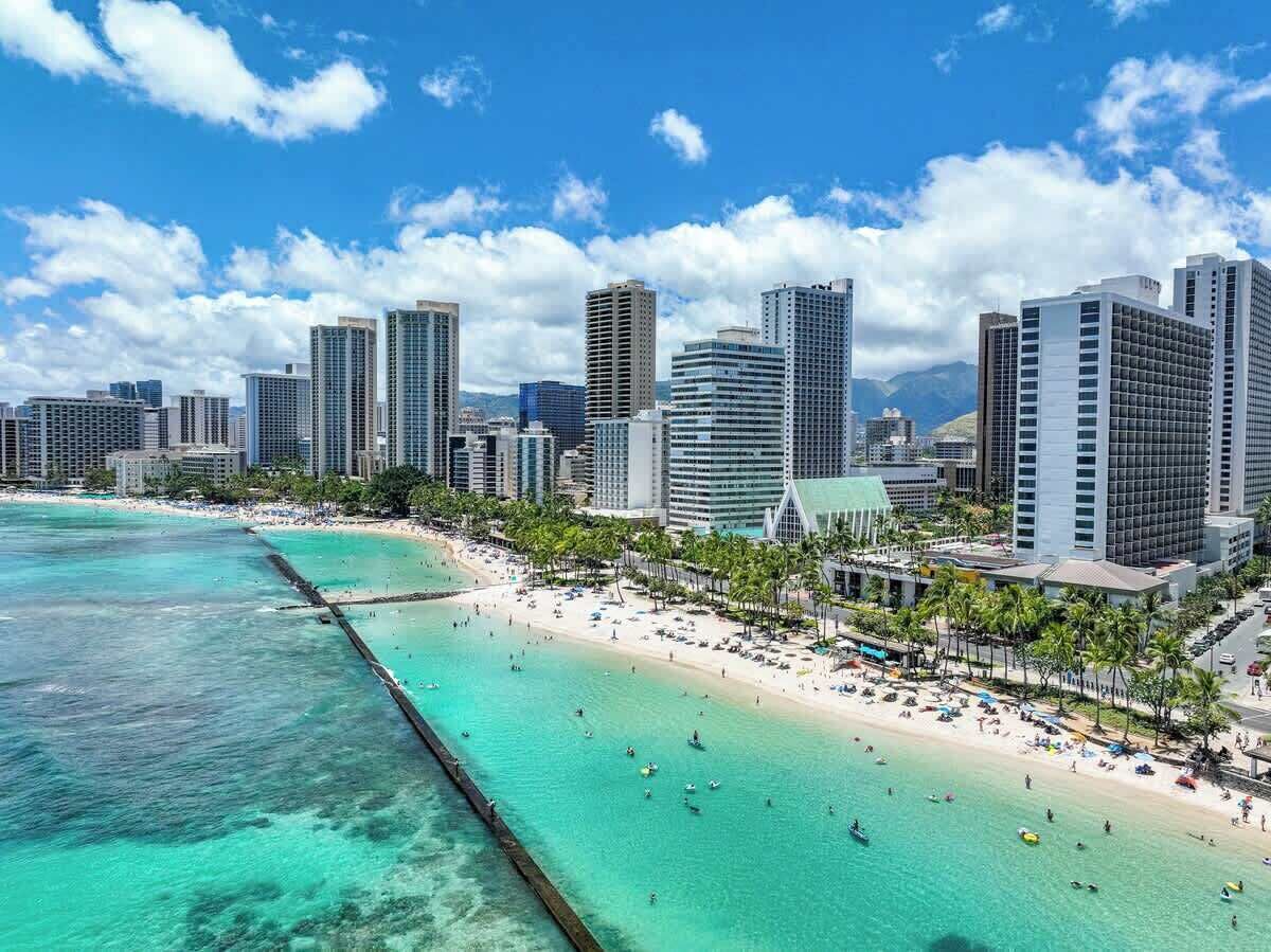 Eine Küstenstadt mit Hochhäusern, einem Strand und klarem türkisblauem Wasser.