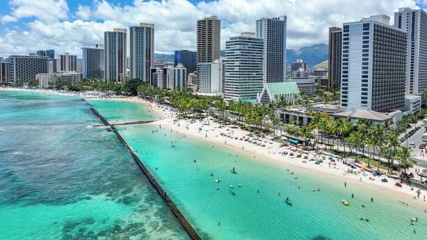 Un paysage urbain côtier avec de hauts immeubles, une plage et une eau turquoise cristalline.