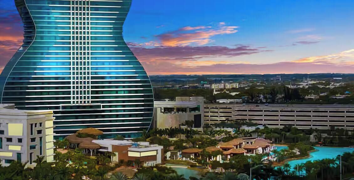 Un hotel moderno con un edificio dalla forma particolare, un parcheggio e una zona piscina.