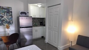 Ett kompakt hotellrum med en säng, ett litet pentry, en matplats och en separat sittgrupp.