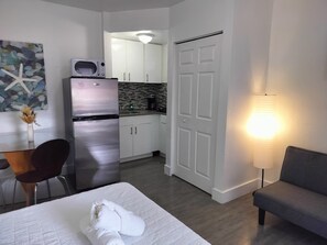 Ein kleines Hotelzimmer mit Bett, einer kleinen Küchenzeile, einem Essbereich und einer separaten Sitzecke.