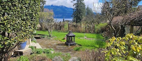 Un jardín con un pabellón, un estanque y vistas a montañas.