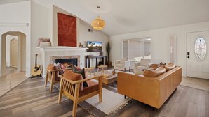Ein Wohnzimmer mit Kamin, Holzmöbeln und einem großen Fenster.