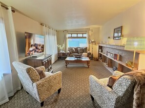 A living room with patterned furniture, a television, a fireplace, and a bookshelf.