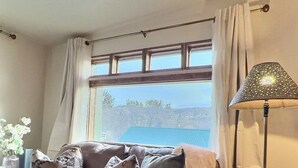 Un salon avec un canapé, une lampe et une vue sur un paysage par la fenêtre.