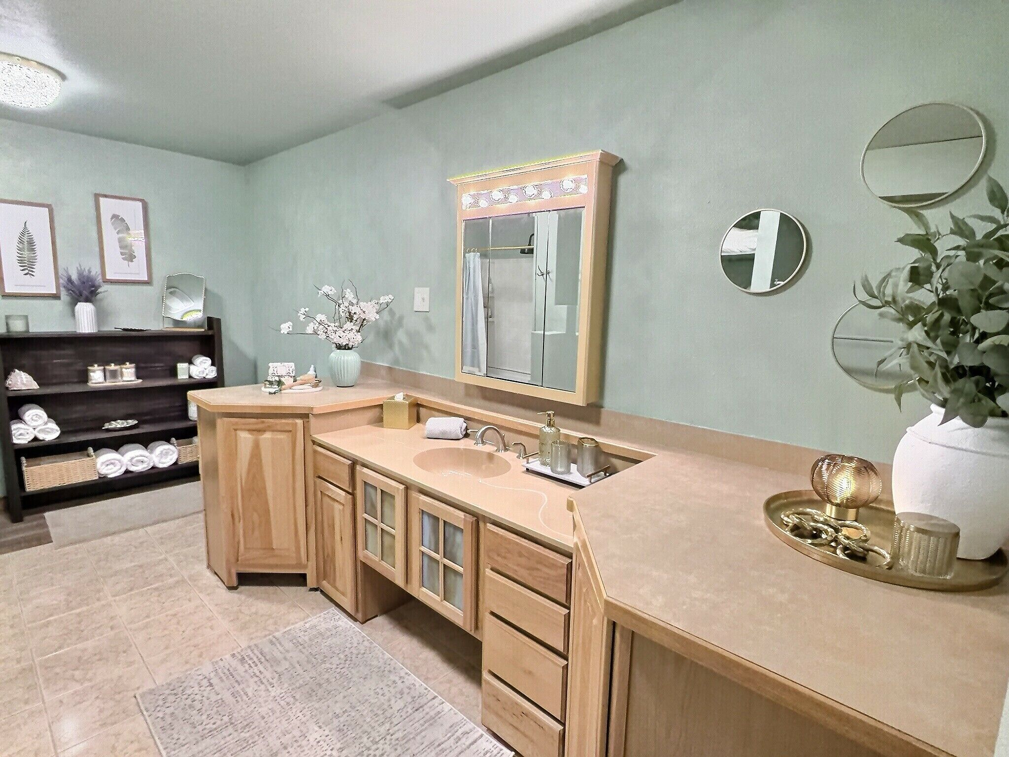 A bathroom with a vanity, a large mirror, a sink, and a shelf with toiletries.