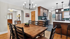 Una cocina moderna con armarios de madera, electrodomésticos de acero inoxidable y un comedor con mesa y sillas de madera.