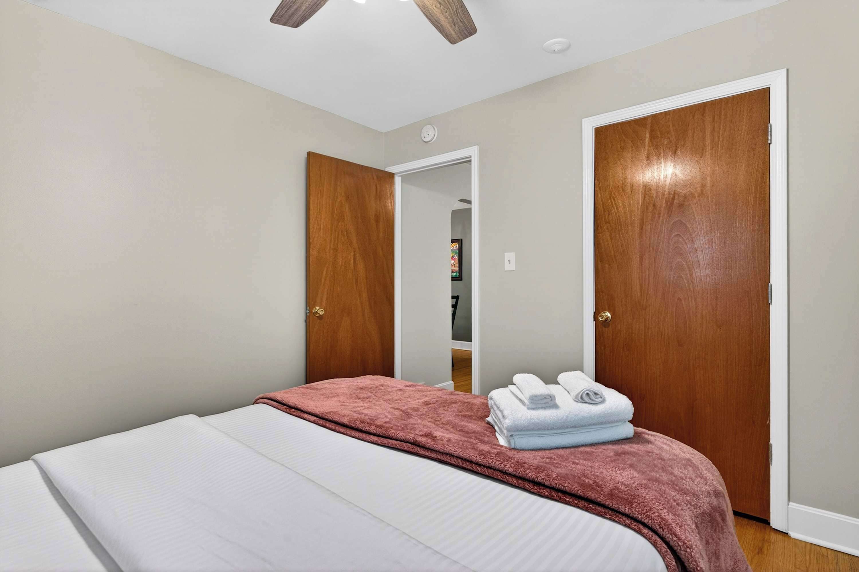 A bedroom with a bed, a wooden door, and a white wall.