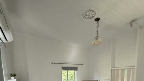 A bedroom with a bed, a window, a radiator, and a ceiling light fixture.