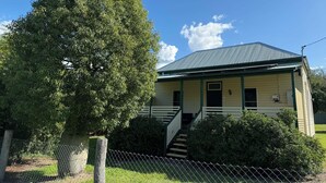 A single-story house with a green roof, a front porch, and a staircase leading to the entrance. - Linville Cottage. This is a 100 year old cottage in town close to rail trail. (Linville)