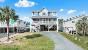 A two-story house with a front porch, a covered walkway, and a small deck. - "Dibbs on Holden" 3 Bedroom, 3 Bathroom, Canal Home (Holden Beach)