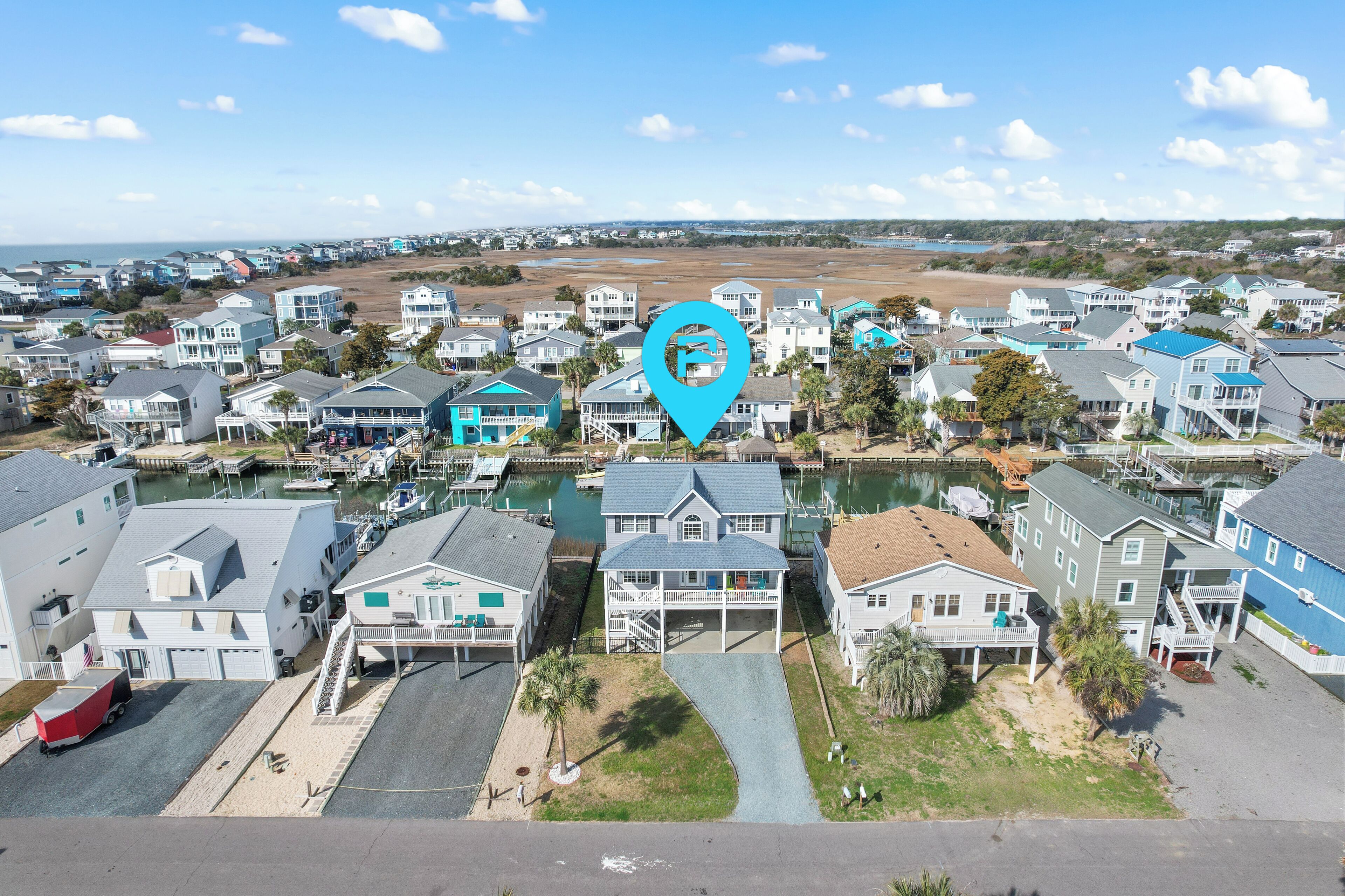 A coastal residential area with houses, a marina, and a clear view of the ocean.