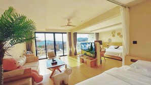 A spacious hotel room with a large bed, a flat-screen TV, a dining area, and a balcony with a view. - Qixiannv Homestay Xiannv Mountain Shop (Chongqing)