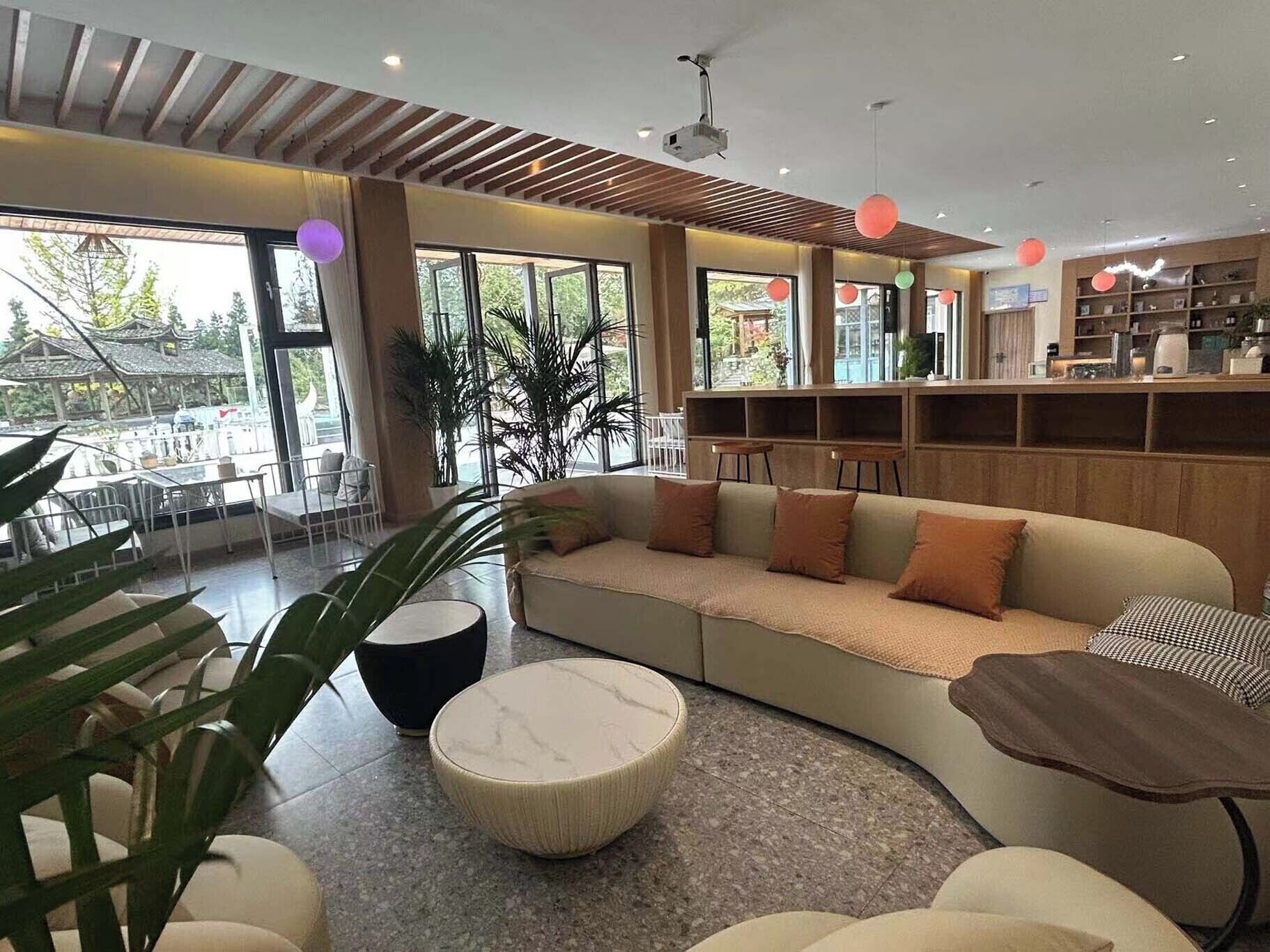 A modern interior with a curved sofa, round ottoman, and a wooden bookshelf.