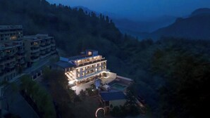 A multi-story hotel with a pool and a view of the surrounding hills. - Qixiannv Homestay Xiannv Mountain Shop (Chongqing)