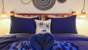 A bed with a blue and black checkered blanket, a wooden headboard, and a wall with circular woven wall hangings. - Casa Kai (Gili Trawangan)
