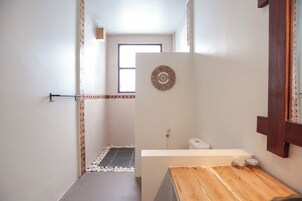 Un baño con ducha, inodoro y tocador de madera.