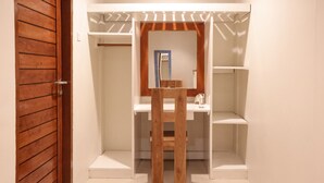 A walk-in closet with wooden doors, a mirror, and built-in shelves. - Casa Kai (Gili Trawangan)