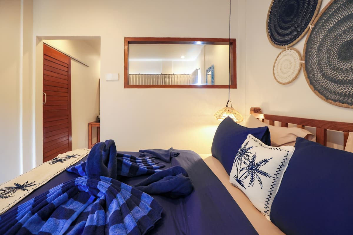 Un dormitorio con cama, espejo y decoración en la pared.