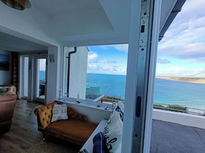 Ein Zimmer mit einem großen Fenster mit Meerblick, einer Couch und einem kleinen Tisch.