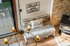 A cozy room with a sofa, a wall sign saying 'RELAX AND UNWIND,' and a fireplace.