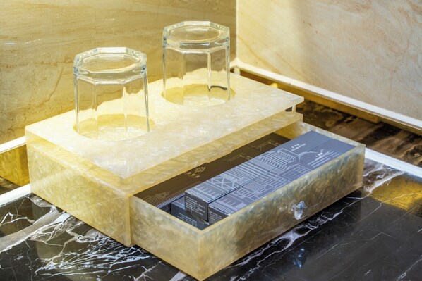 Eine transparente Glasvitrine mit zwei Glas Hockern darauf, auf einer Marmorplatte platziert.