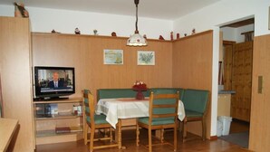 Ein Essbereich mit Holztisch, Stühlen, Fernseher und einer Couch.