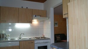 Eine Küche mit Holzausbau, einer Edelstahlspüle, einem Einbauofen und einer Arbeitsplatte mit Geschirrständer.