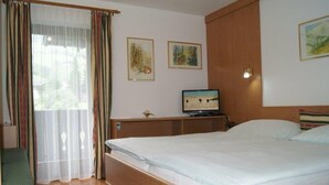 Ein Hotelzimmer mit Bett, Fernseher, Schreibtisch und einem Fenster mit Vorhängen.