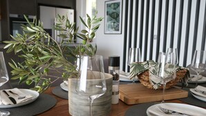 A dining table set with plates, cutlery, and a glass vase with green foliage. - Moderne Villa mit Infinity-Pool im Bergdorf Veliko Brdo by Interhome (Makarska)