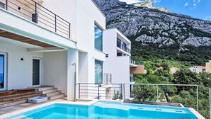 A modern two-story building with a swimming pool, a staircase, and a mountain view. - Moderne Villa mit Infinity-Pool im Bergdorf Veliko Brdo by Interhome (Makarska)