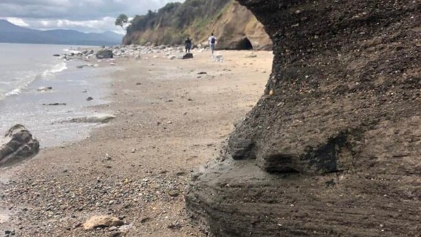 A beach with a large rock formation, a sandy shore, and a few people in the distance. - Hot Tub Getaway, Snowdon Views, Peaceful Stay (Llanfairpwllgwyngyll)