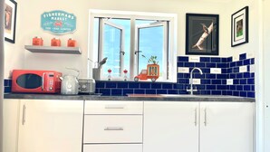 A kitchen with a red microwave, a toaster, a coffee maker, a sink, and a window with a view. - Hot Tub Getaway, Snowdon Views, Peaceful Stay (Llanfairpwllgwyngyll)