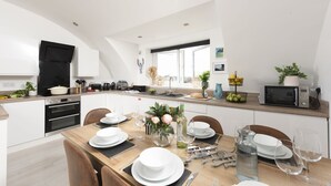 Eine moderne Küche mit Essbereich, ausgestattet mit Herd, Backofen und Mikrowelle.