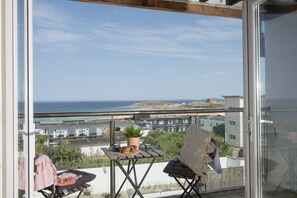 Ein Balkon mit Meerblick, ein Tisch mit einer Pflanze und ein Stuhl.