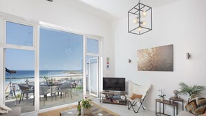 Ein geräumiges Wohnzimmer mit einem großen Schiebeglasfenster, das auf einen Balkon mit Meerblick führt.