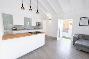 Una cocina moderna con armarios blancos, encimera de madera y microondas integrado.